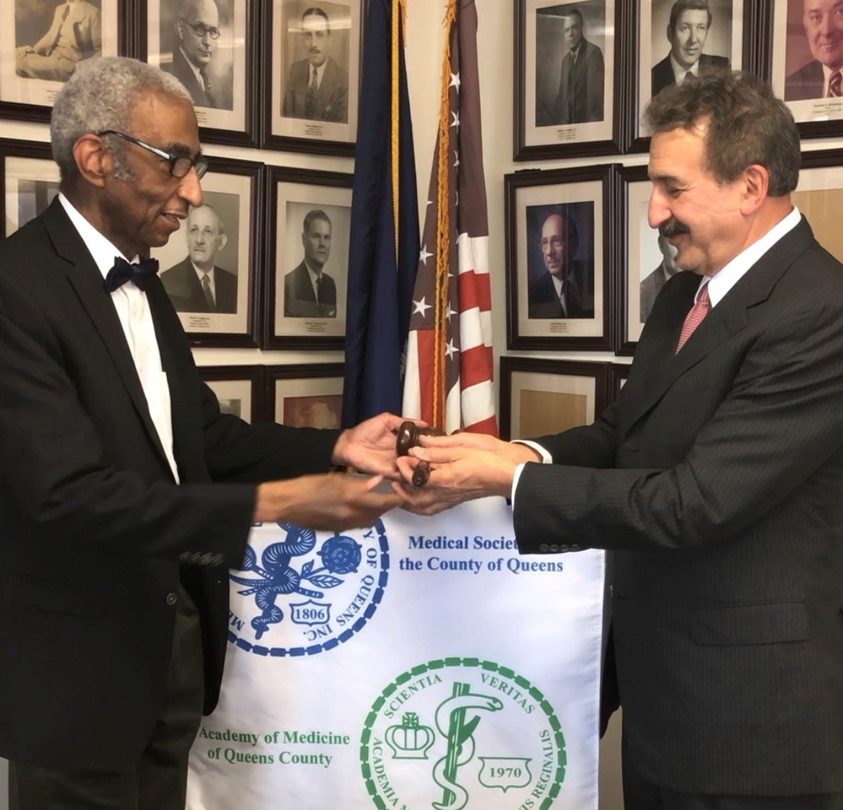 Passing of the gavel in front of the MSCQ and Academy of Medicine banner